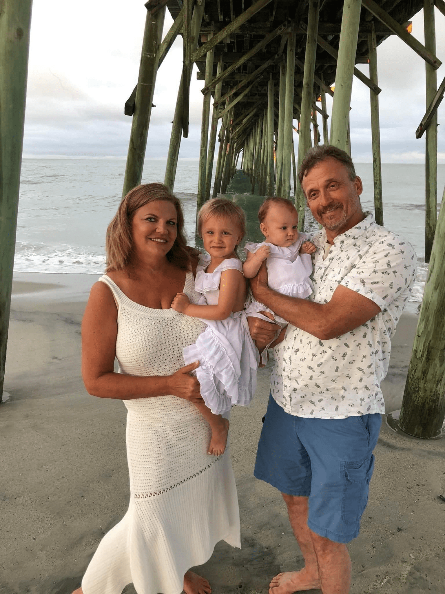 A family posing for a picture under a pier.